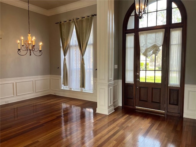 entryway featuring dark hardwood / wood-style floors, crown molding, a wealth of natural light, and a chandelier