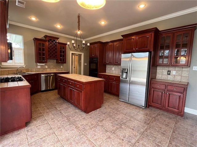 kitchen with decorative backsplash, a kitchen island, crown molding, and appliances with stainless steel finishes