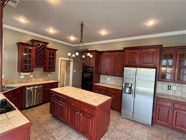 kitchen featuring black appliances, decorative backsplash, a kitchen island, and tile countertops