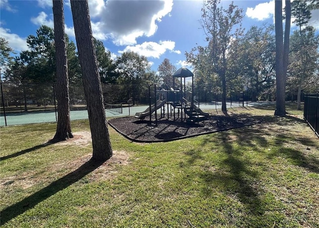 view of jungle gym featuring a lawn and tennis court