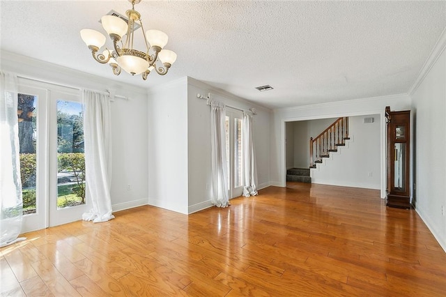 unfurnished room featuring crown molding, hardwood / wood-style floors, a textured ceiling, and an inviting chandelier