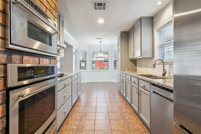 kitchen featuring gray cabinets, sink, stainless steel appliances, and plenty of natural light