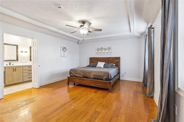 bedroom featuring ensuite bathroom, a textured ceiling, ceiling fan, sink, and light hardwood / wood-style flooring