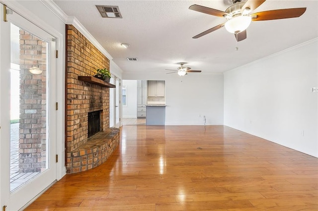 unfurnished living room featuring a fireplace, crown molding, light hardwood / wood-style flooring, and a textured ceiling