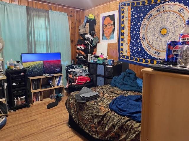 bedroom featuring wood walls and wood-type flooring