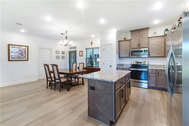 kitchen with pendant lighting, a center island, crown molding, light hardwood / wood-style floors, and stainless steel appliances