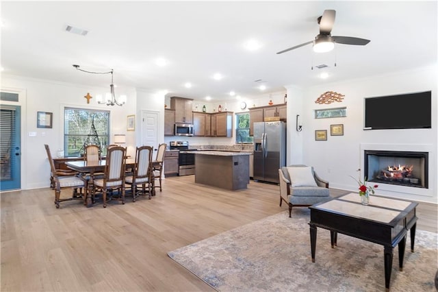 living room featuring plenty of natural light, light hardwood / wood-style floors, ceiling fan with notable chandelier, and ornamental molding