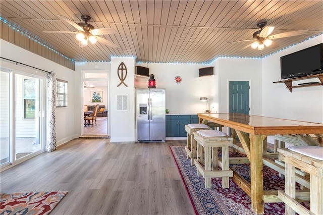 unfurnished dining area featuring ceiling fan, wooden ceiling, and light wood-type flooring