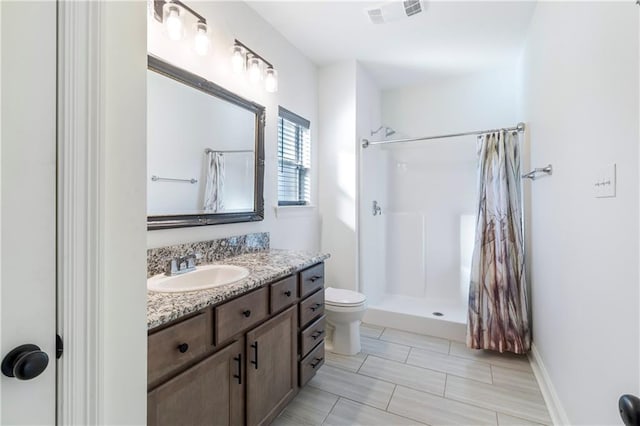 bathroom with toilet, vanity, and walk in shower