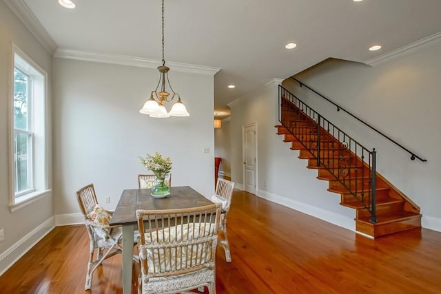 dining space with hardwood / wood-style flooring, ornamental molding, and a notable chandelier