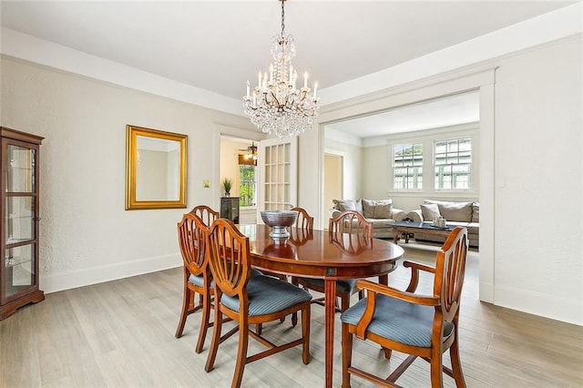 dining area with light hardwood / wood-style floors and a chandelier