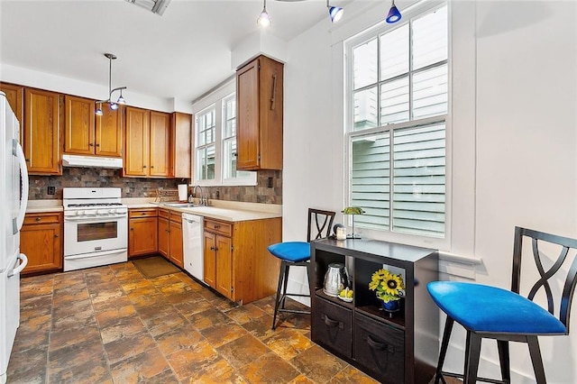 kitchen with decorative backsplash, sink, pendant lighting, and white appliances