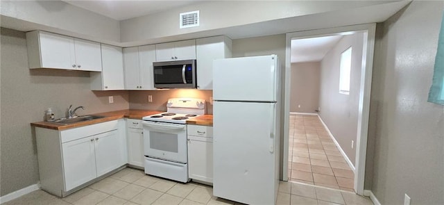 kitchen with light tile patterned floors, white appliances, white cabinetry, and sink