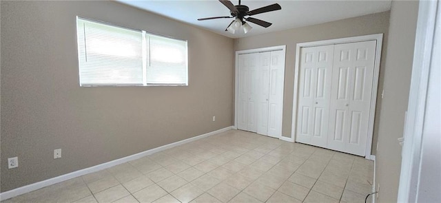 unfurnished bedroom featuring ceiling fan, light tile patterned floors, and multiple closets