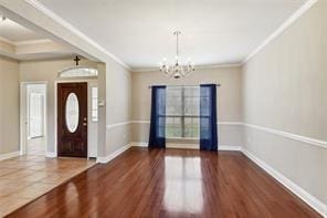 entrance foyer featuring crown molding, dark hardwood / wood-style flooring, and a notable chandelier