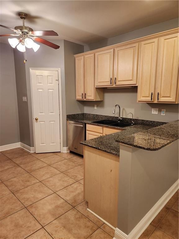 kitchen featuring sink, stainless steel dishwasher, dark stone countertops, kitchen peninsula, and light tile patterned floors