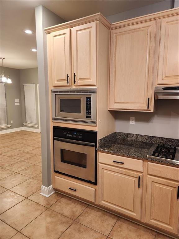 kitchen featuring appliances with stainless steel finishes, light brown cabinets, decorative light fixtures, a notable chandelier, and light tile patterned flooring