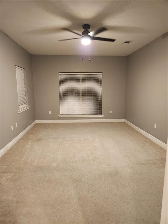 spare room with ceiling fan and light colored carpet