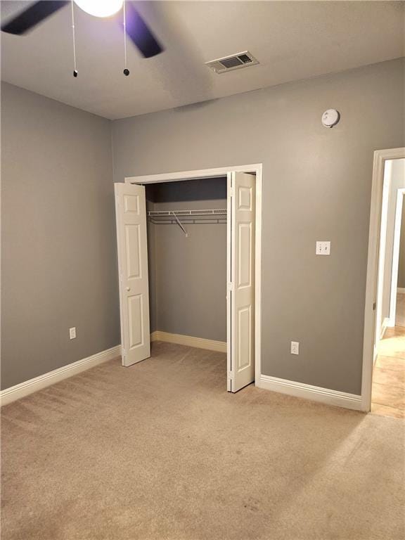 unfurnished bedroom with ceiling fan, light carpet, and a closet