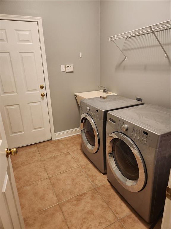 clothes washing area featuring independent washer and dryer, sink, and light tile patterned floors