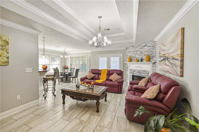 living room featuring an inviting chandelier, a raised ceiling, a stone fireplace, a textured ceiling, and ornamental molding