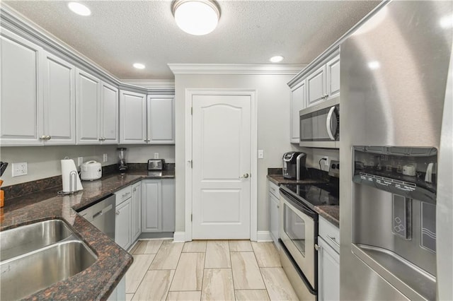 kitchen featuring dark stone counters, a textured ceiling, stainless steel appliances, crown molding, and gray cabinets