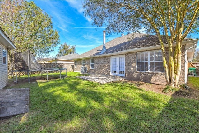 rear view of house with french doors, a yard, a trampoline, and a patio