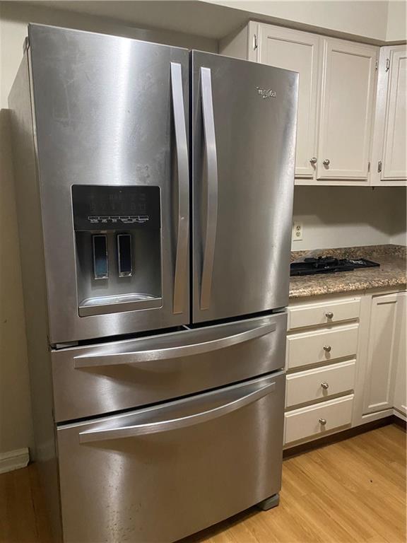 kitchen featuring stainless steel fridge, white cabinetry, and light hardwood / wood-style floors