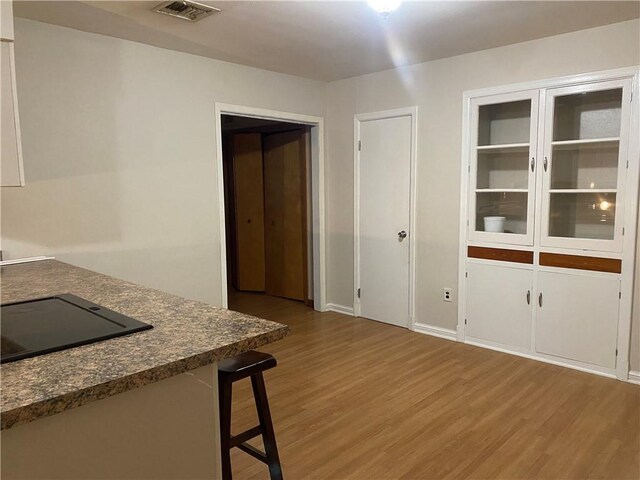 kitchen featuring a breakfast bar, wood-type flooring, and black electric stovetop