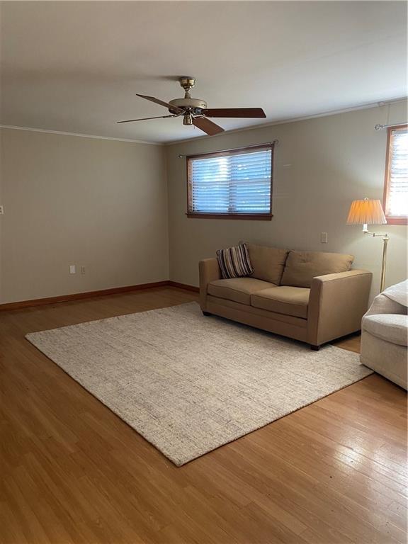 unfurnished living room with hardwood / wood-style flooring, crown molding, and ceiling fan