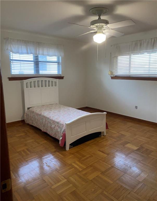 bedroom with ceiling fan, multiple windows, and parquet floors