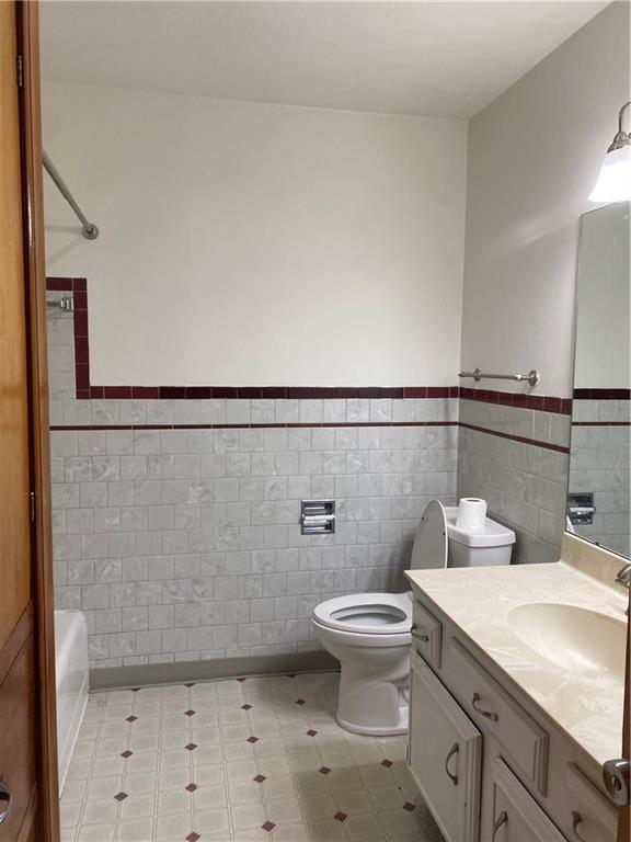 bathroom featuring toilet, tile walls, and vanity