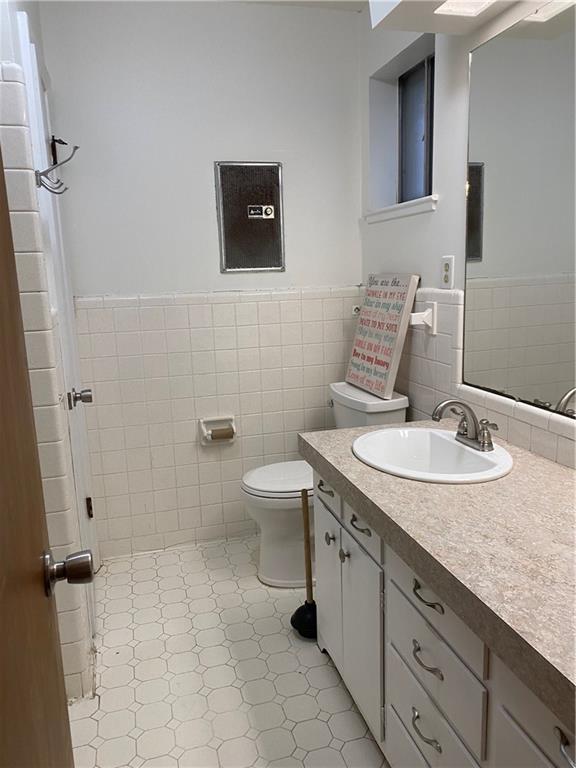 bathroom featuring toilet, tile walls, and vanity