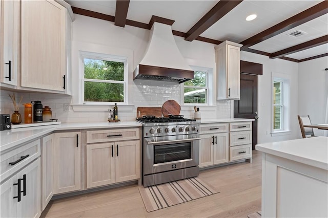 kitchen featuring beam ceiling, tasteful backsplash, light hardwood / wood-style flooring, premium range hood, and high end stainless steel range