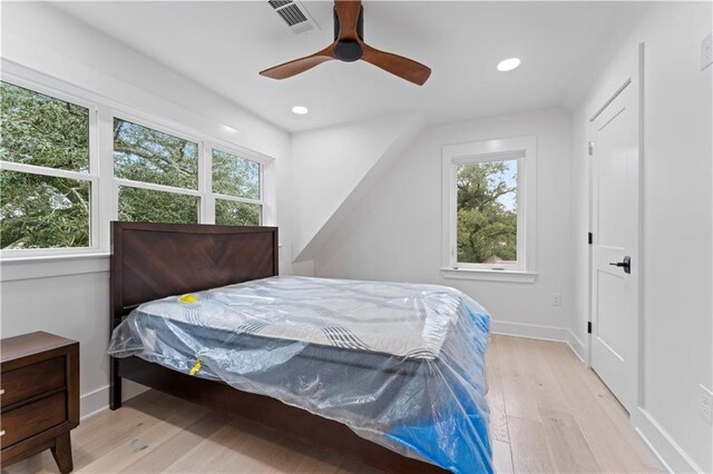 bedroom with ceiling fan, light wood-type flooring, and multiple windows