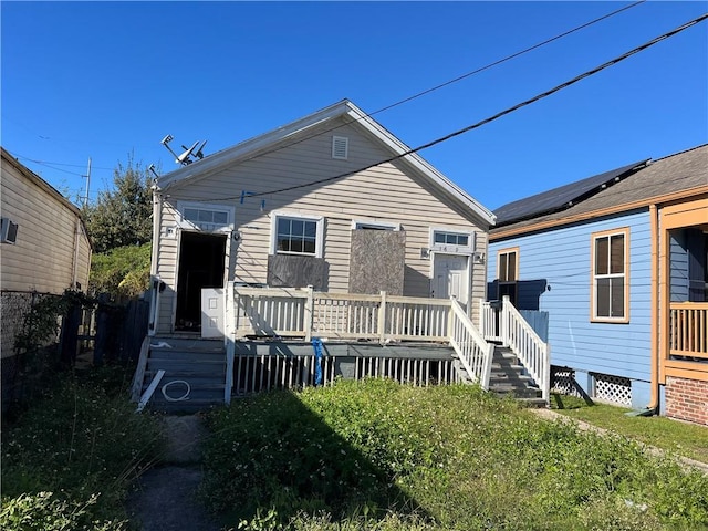 rear view of property with solar panels and a wooden deck