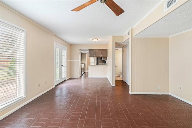 unfurnished living room featuring ceiling fan, french doors, a textured ceiling, and ornamental molding