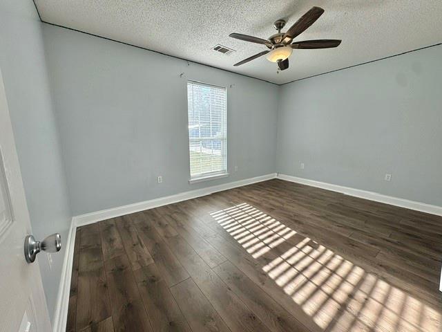 unfurnished room with ceiling fan, dark wood-type flooring, and a textured ceiling