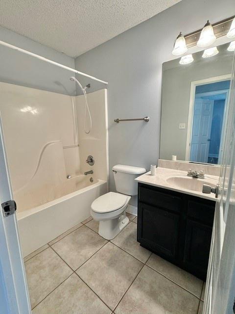 full bathroom with tub / shower combination, vanity, a textured ceiling, tile patterned flooring, and toilet