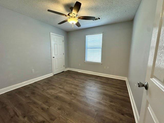 unfurnished room featuring dark hardwood / wood-style floors, ceiling fan, and a textured ceiling