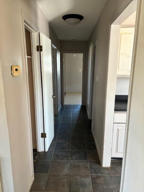 hallway featuring dark tile patterned floors