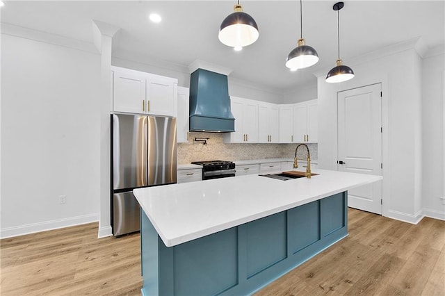 kitchen with white cabinets, sink, stainless steel fridge, custom range hood, and black range with gas cooktop