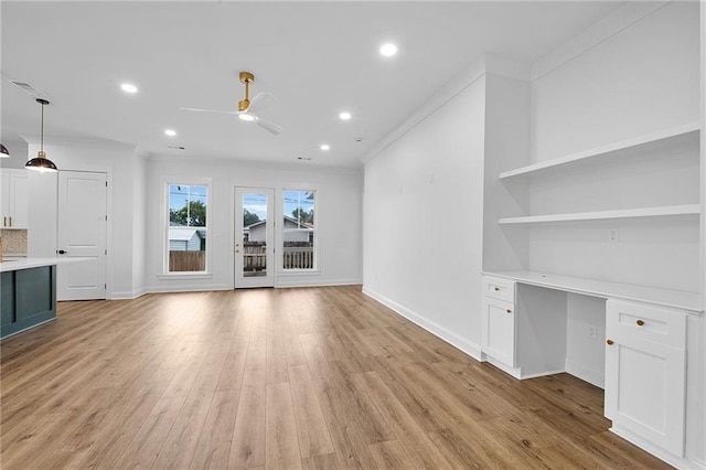 unfurnished living room featuring ceiling fan, light wood-type flooring, built in desk, and ornamental molding