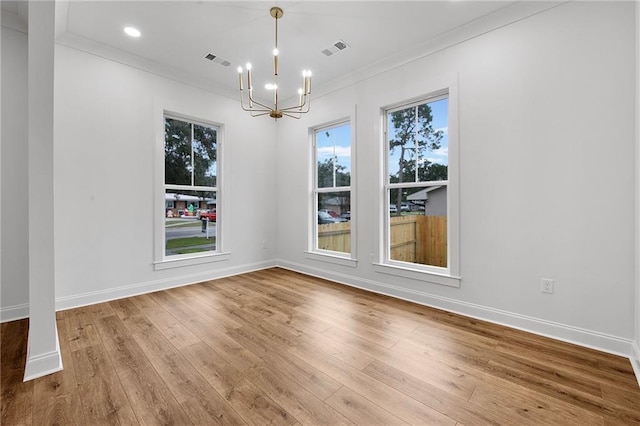 unfurnished dining area with hardwood / wood-style flooring, ornamental molding, and an inviting chandelier