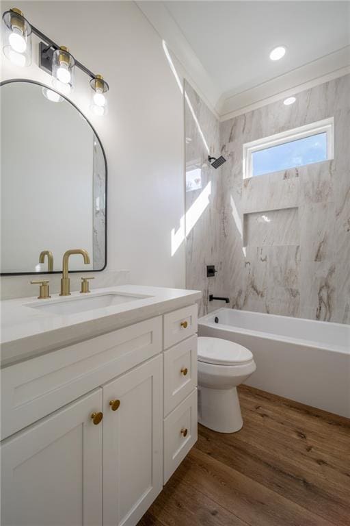 full bathroom featuring hardwood / wood-style floors, vanity, tiled shower / bath, toilet, and ornamental molding