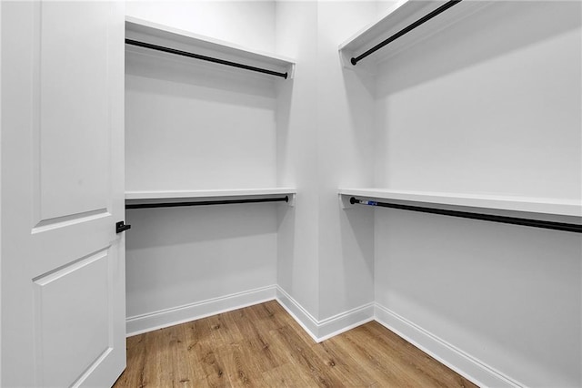 walk in closet with light hardwood / wood-style floors