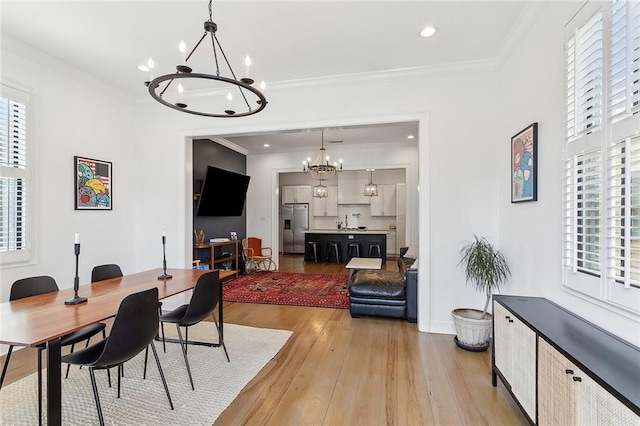 dining room featuring a chandelier, light hardwood / wood-style floors, a wealth of natural light, and crown molding