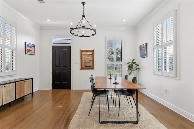 dining room featuring a healthy amount of sunlight, wood-type flooring, and a chandelier