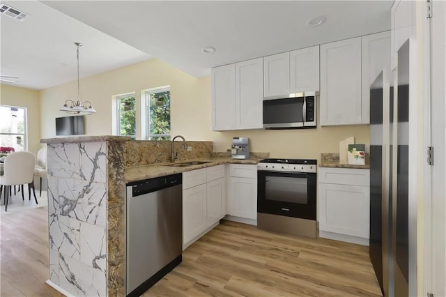 kitchen with kitchen peninsula, plenty of natural light, white cabinets, and appliances with stainless steel finishes