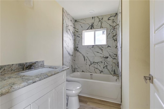 full bathroom featuring vanity, hardwood / wood-style flooring, toilet, and tiled shower / bath combo